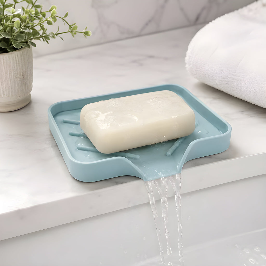 HomeShape light blue silicone self-draining soap tray with bar soap on a marble bathroom countertop